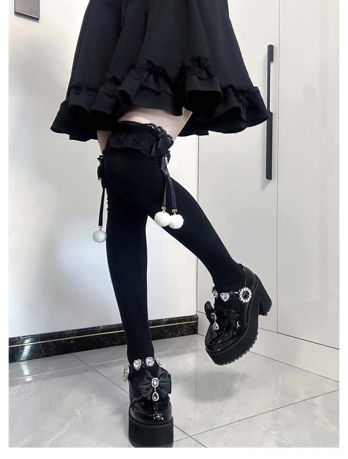 Jirai Kei mid-calf socks black colorway side view showing solid black sock with lace trim and pom-pom accent paired with ruffled mini skirt and platform loafer