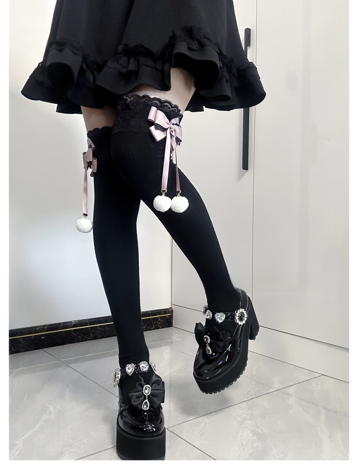Jirai Kei mid-calf socks black-pink colorway front view showing contrast pink bow and white pom-pom on black sock with lace cuff styling with platform shoes