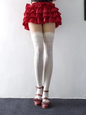 Milky white diamond fishnet stockings with lace ruffle cuffs worn with red ruffle mini skirt and vintage heeled shoes, showing full knee-high length and geometric cutout pattern