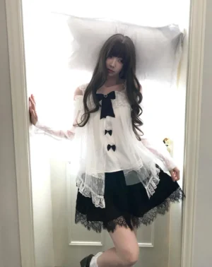 Jirai Kei off-shoulder blouse with detachable bows and swan feather tulle skirt set worn indoors, showing full-body front view of black-and-white lace ensemble with ruffled collar and layered skirt