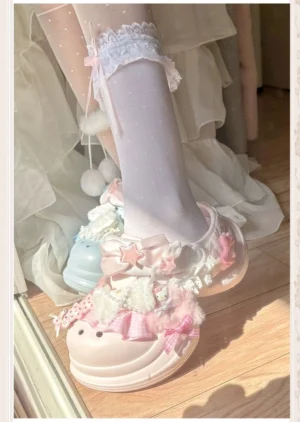 Pastel pink Jirai Kei kawaii thick-soled clog sandal with lace trim, fuzzy pom-poms, cute bow details, and star charms, worn with white sheer lace socks