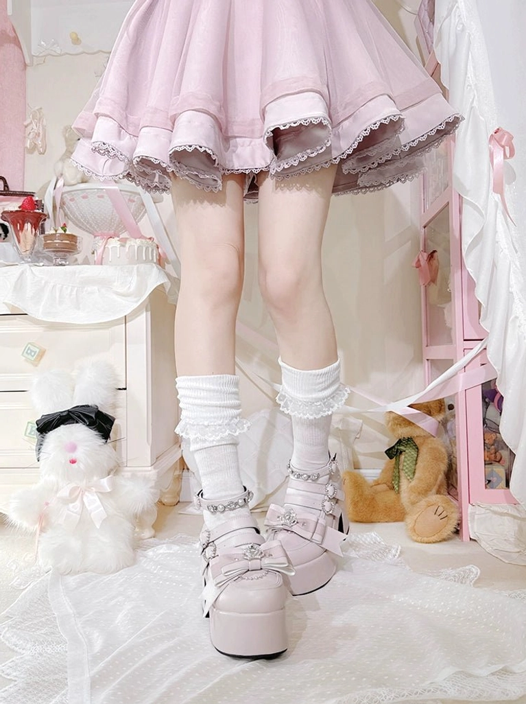 Pastel pink Jirai Kei platform heels with rhinestone details and thick block heel, styled in feminine bedroom environment with accessories