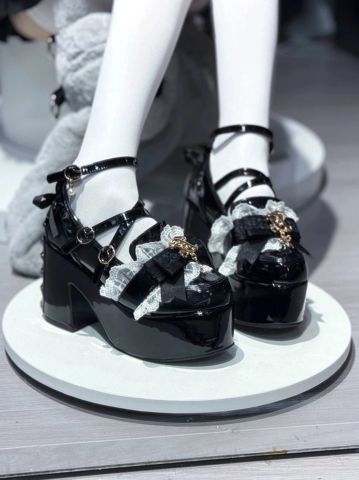 Jirai Kei patent leather platform heel close-up showing gold charm ornaments metal logo details and decorative lace trim design elements subcultural significance