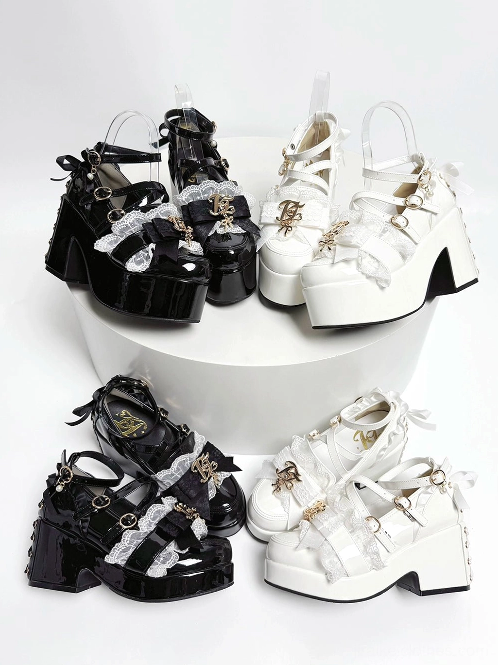 Jirai Kei platform heels flat lay top view showing patent leather black and white colorways with crisscross buckle straps and gold charm details