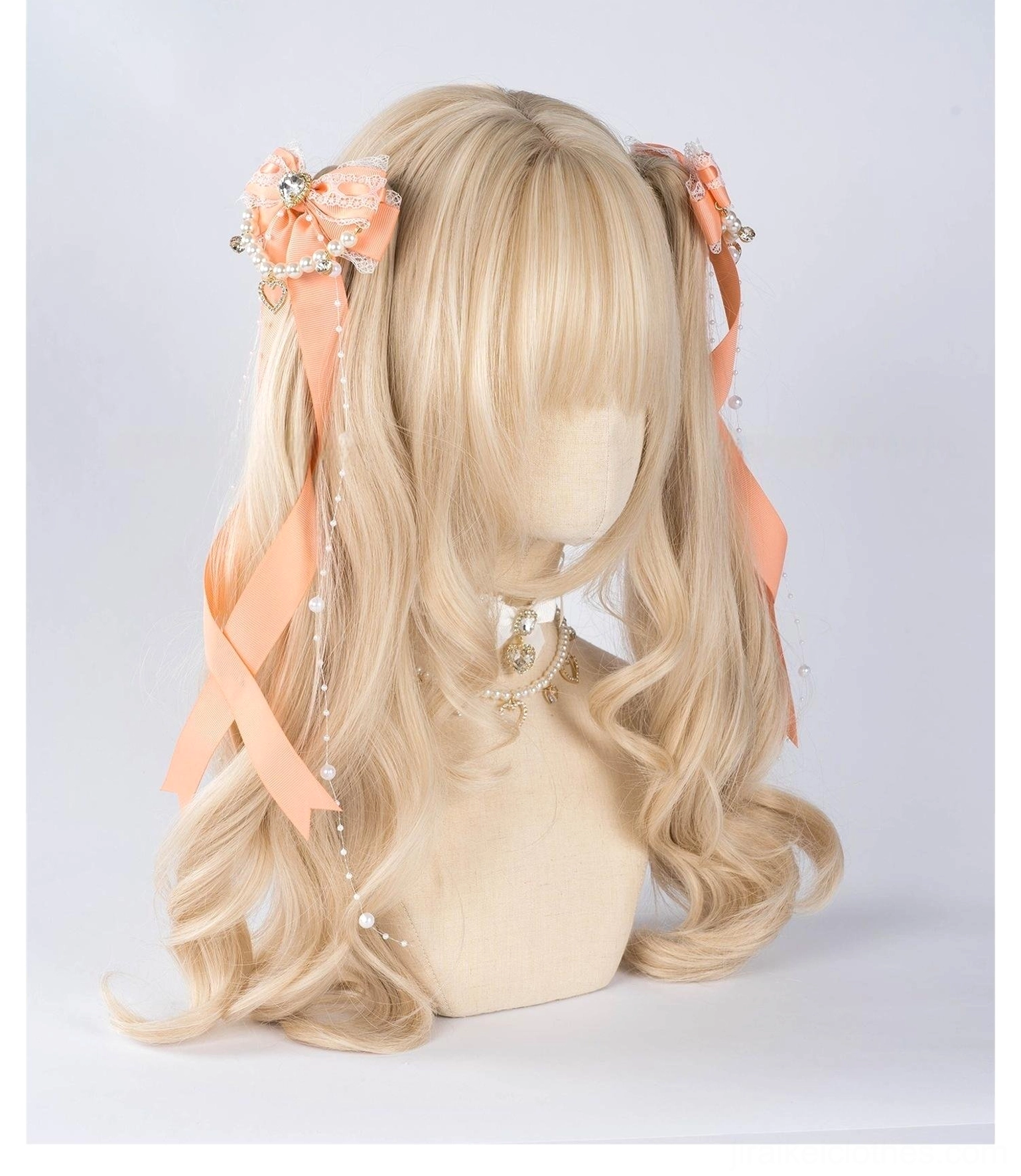 Jirai Kei peach pink bow hair clips with ribbon fabric and pearl chain trim paired with peach-toned accessory details on mannequin head