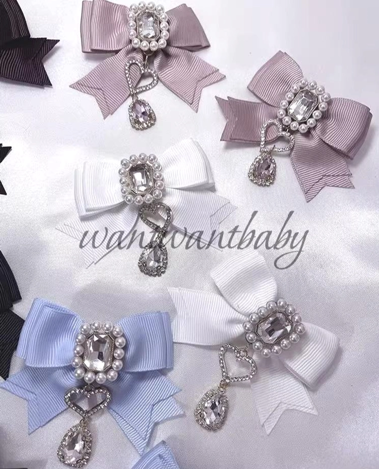 Multiple Jirai Kei bow hair clips in various colors arranged on studio backdrop showing rhinestone ornament details and teardrop pendants