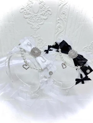 Black and white Jirai Kei pearl bow headband with heart-shaped rhinestone charm and lace details flat lay