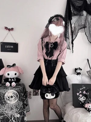 Gothic lolita two-piece outfit with pink blouse and black ruffle skirt model holding themed handbag with black bow tie corset waist