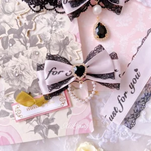 Pink-black Jirai Kei double bow choker with pearl chain trim and oversized mini bow accessories on vintage floral printed background