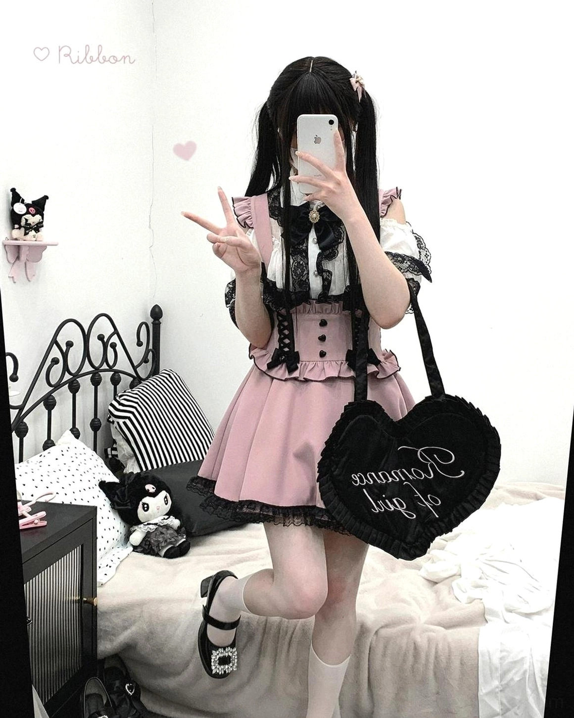 Pink and black Jirai Kei lace cold-shoulder blouse with bow tie, petal-shaped lace collar detail, full front view on model in bedroom setting