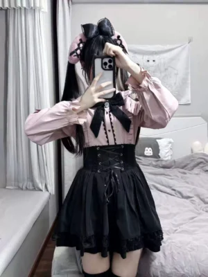 Jirai Kei pink and black two-piece outfit featuring lace-shoulder pink blouse with ruffled details, high-waist black mini skirt with front corset lace-up, black bow tie collar, perfect fragile aesthetic ensemble