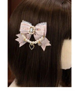 Pink lace bow Jirai Kei hair clip with pearl chain and rhinestone details displayed on mannequin wig rear view showcasing delicate design