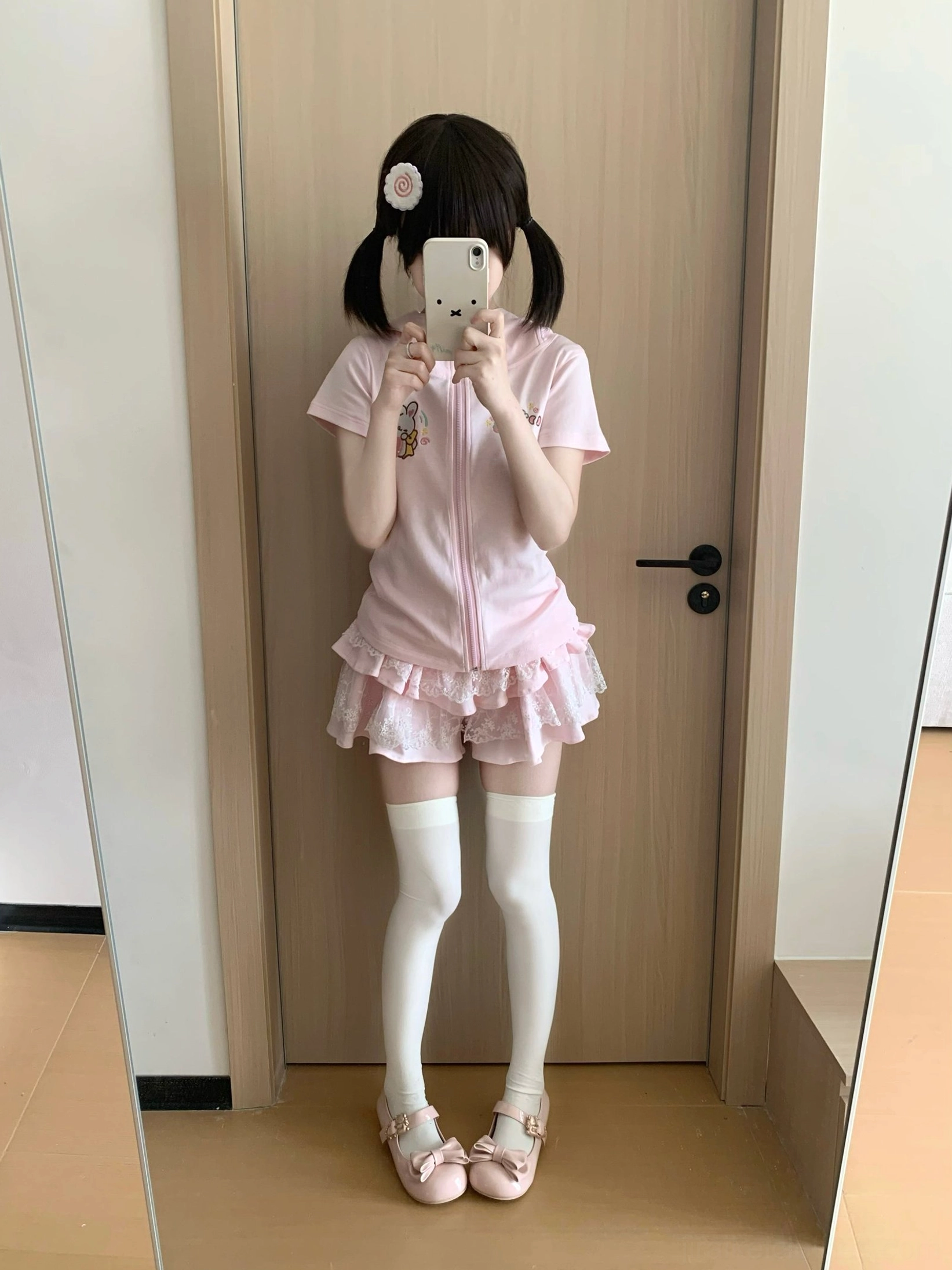 Pink Jirai Kei zip-up bunny-ear hoodie with ruffle mini skirt worn in first-person selfie with white thigh-highs pink ballet flats and twin-tails