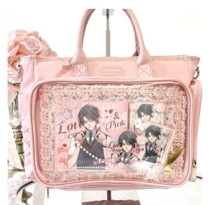 Pink Jirai Kei itabag with transparent anime character display window, lace trim, and decorative silk rose styling, flat lay overhead view