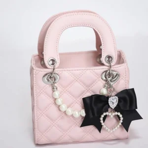 Pink Jirai Kei mini quilted tote bag with pearl chain strap and black heart crystal bow charm on white background front view