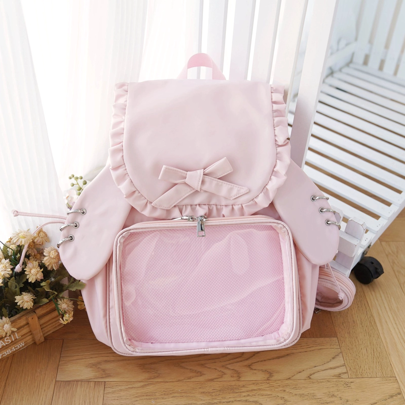 Sakura pink Jirai Kei itabag backpack with cute bunny ears, large clear acrylic window for badge display, pink ruffled bow, and coordinating pouch