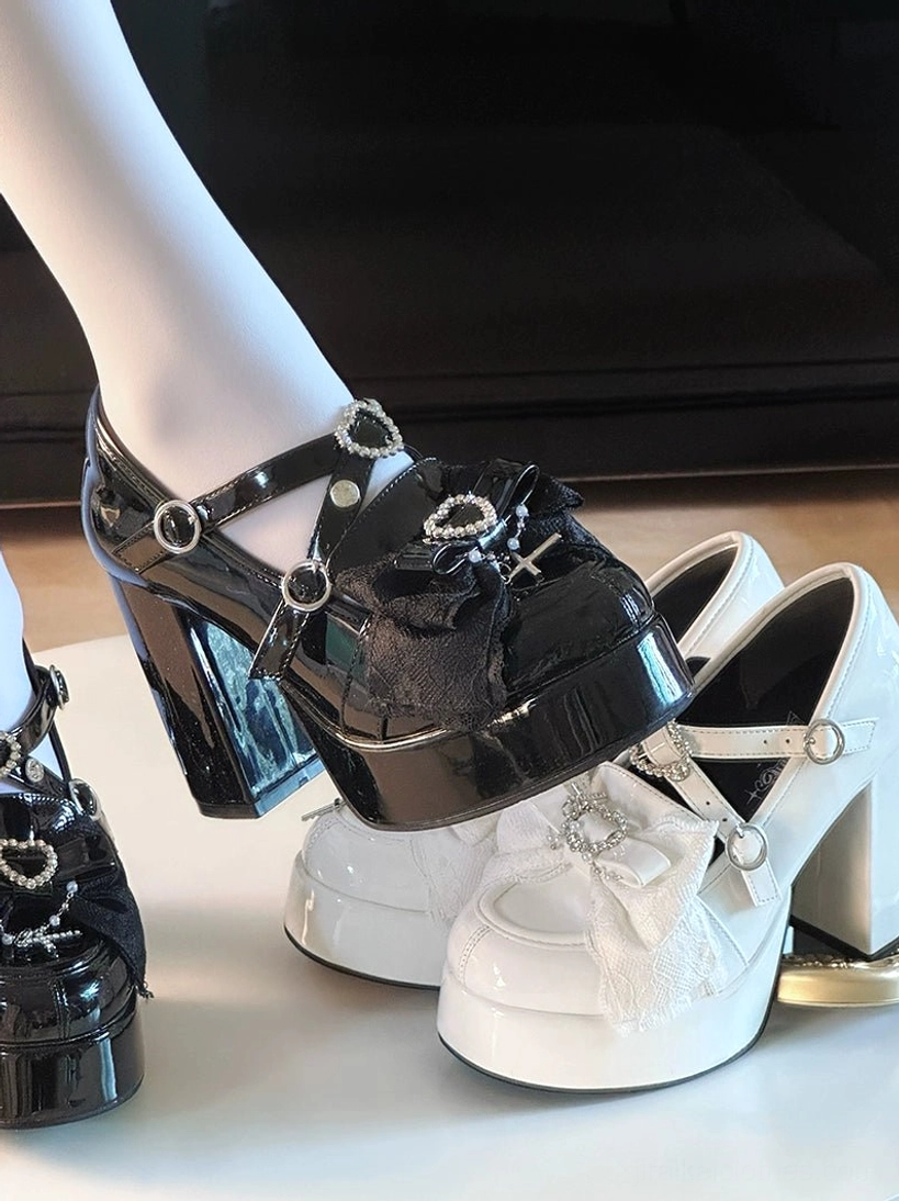 Detailed view of black Jirai Kei platform heel shoes highlighting heart-shaped rhinestone embellishments, adjustable buckle strap system, and glossy patent leather construction