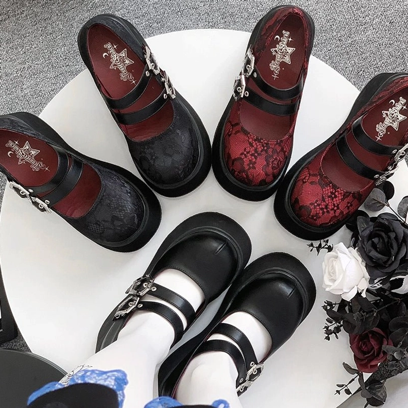 Multiple pairs of Mary Jane platform shoes in color variants with dual silver buckles and thick platform soles displayed on white table with gothic decor