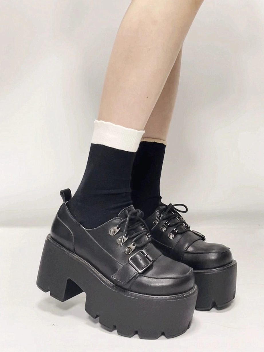 Side view of black platform derby shoe displaying decorative buckle strap high block heel and smooth leather upper on lower leg
