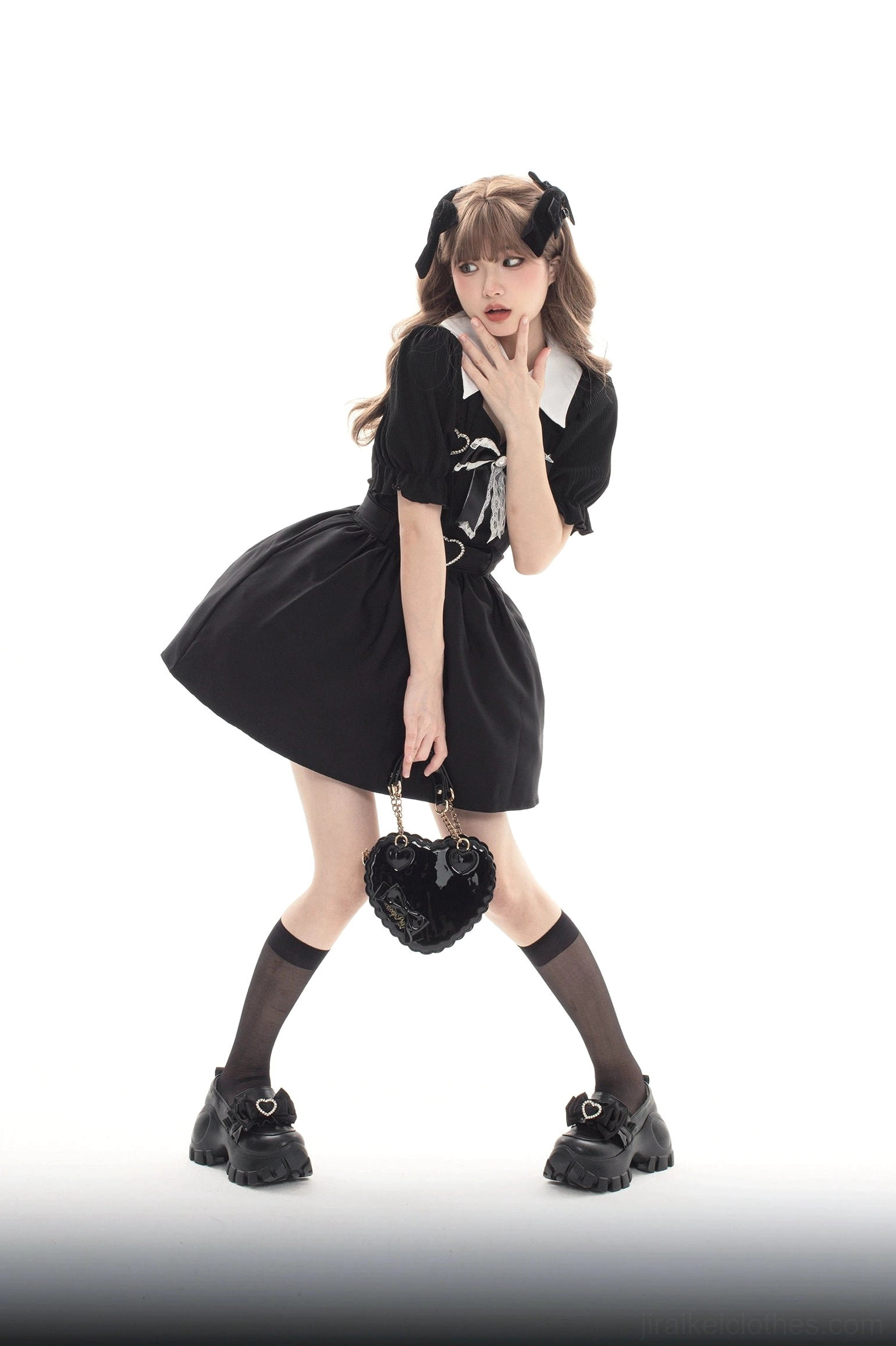 Full-body model wearing black JK platform shoes with chunky lug sole, paired with black dress and knee-high socks against white studio background
