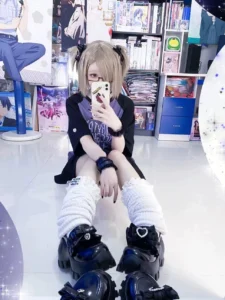 Low-angle close-up of black JK platform shoes with heart gem bow and thick sole, styled with fluffy white leg warmers in anime store setting