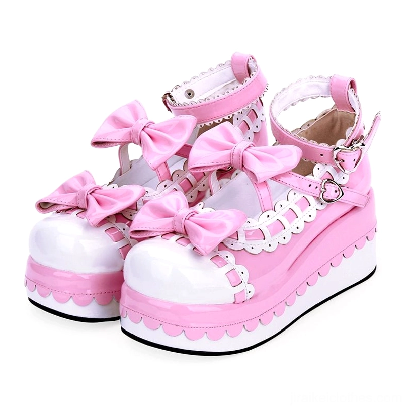 Pink leather white trim Jirai Kei platform shoes with bow decorations and heart-shaped buckle ankle strap front three-quarter view