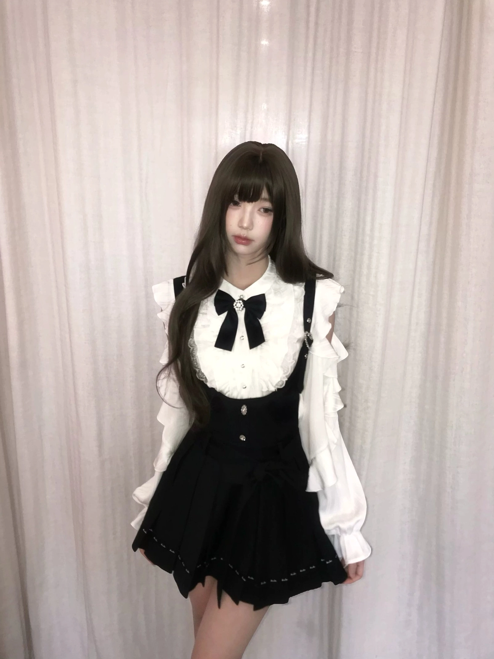 Jirai Kei pleated suspender skirt with ruffled off-shoulder white blouse full-body front view model wearing complete set with black bow collar and heart-shaped buckles