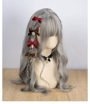 Red and dark brown Jirai Kei bow hair clips with rhinestone and bell charm pendants displayed on gray wavy wig model with lace choker accessory