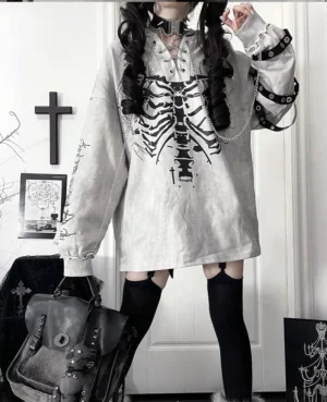 Gray and white ribcage print Jirai Kei hoodie with cat ear hood and metal buckle arm straps, worn by model with twin tails in gothic decorated room, full-body front view showcasing oversized fit and anatomical graphic design