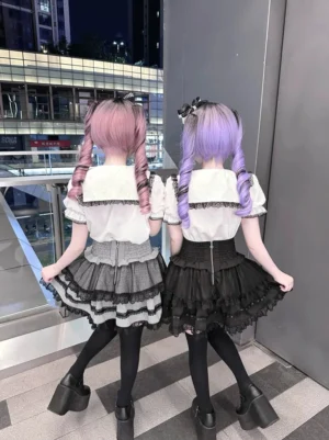 Sailor collar Jirai Kei blouse and high waist cinched skirt back view - showing layered ruffle tiered skirt design with back zipper and heart rhinestone embellishments, modeled with black thigh-high socks and platform shoes
