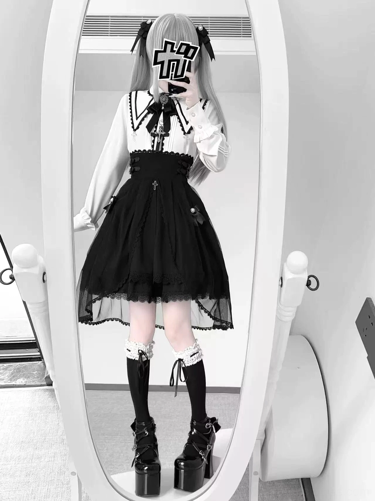 Alternative color styling Jirai Kei outfit showing white sailor-inspired collar blouse paired with black tulle high-waist skirt featuring lace-up back details and decorative buckles, full-body mirror view with platform boots and lace stockings