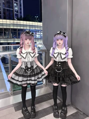 Jirai Kei sailor collar blouse with tiered ruffle skirt front view - white blouse with heart-shaped buttons and black lace trim paired with cinched waist tiered ruffle skirt, modeled outdoors at night with matching platform shoes