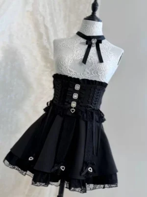 Black and white Jirai Kei lace skirt set displayed on dress form, showing corset lace-up waist, heart rhinestone button details, and tiered ruffle lace hem