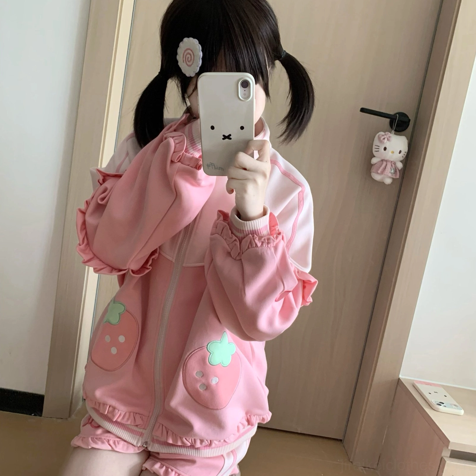 Top-down flat lay of pink strawberry Jirai Kei shorts with bow embroidery and ruffled hem, showcasing side pockets and elastic waistband construction details