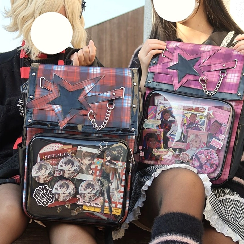 Two subculture-style models wearing red and purple plaid star ita backpacks with anime badge displays