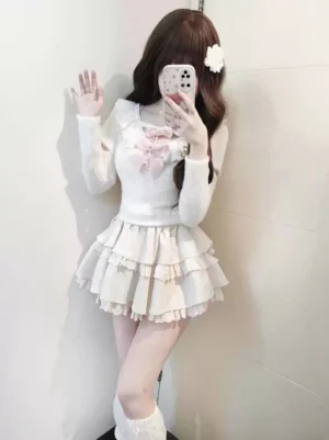 Ivory Jirai Kei sweater and mini ruffle skirt ensemble photographed from front angle showing V-shaped collar with flounce trim and layered skirt construction, model wearing coordinating white accessories