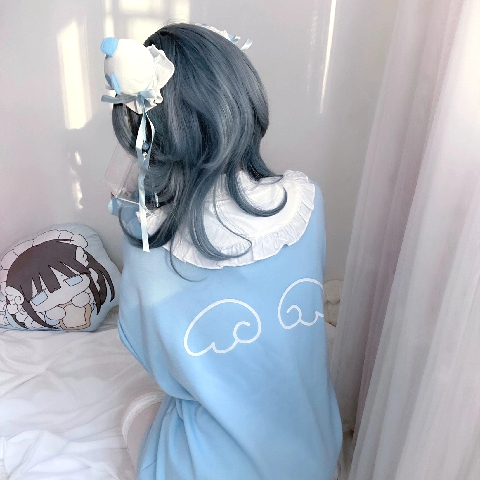 Back view close-up of light blue Jirai Kei sweatshirt showing wing embroidery on rear, white ruffled collar, and playful celestial-inspired design elements