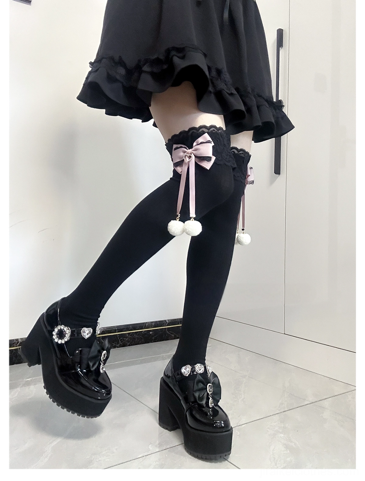 Matching Jirai Kei thigh-high socks low-angle front posed view solid black socks lace cuffs matching pink bows with hanging white pom-pom accents platform loafer styling