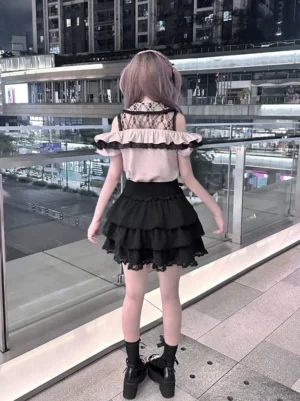 Gothic lolita two-piece ensemble back view showing exposed lace yoke and ruffled tiered black skirt with heart-shaped waist buckles, worn at outdoor urban night venue