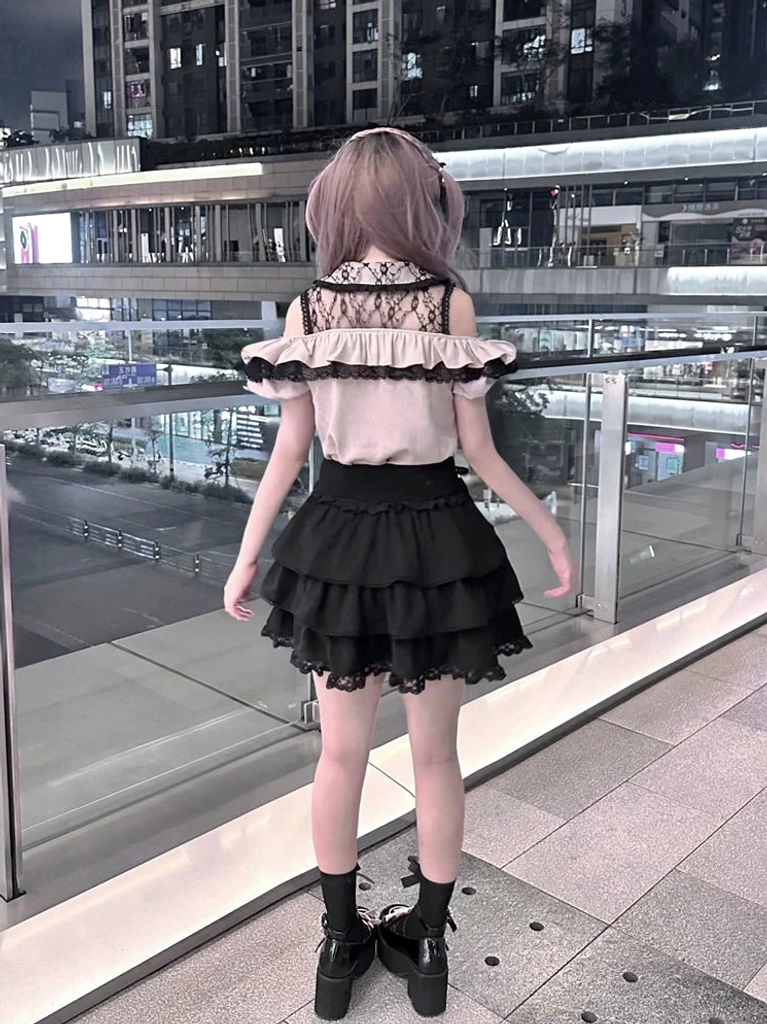 Gothic lolita two-piece ensemble back view showing exposed lace yoke and ruffled tiered black skirt with heart-shaped waist buckles, worn at outdoor urban night venue