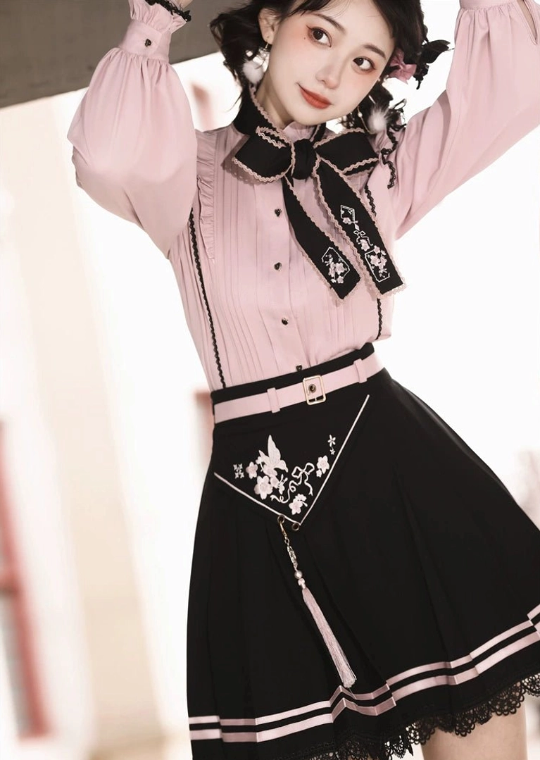 Full body Jirai Kei outfit with arms raised, showing button-down pink blouse, high-waisted pleated black skirt, and complete silhouette on European street background