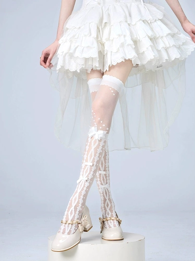 White Jirai Kei over-the-knee socks with bow and dot details combined with delicate lace trim, front low-angle view on model in white ruffled skirt and beige Mary Jane shoes, highlighting refined pattern placement