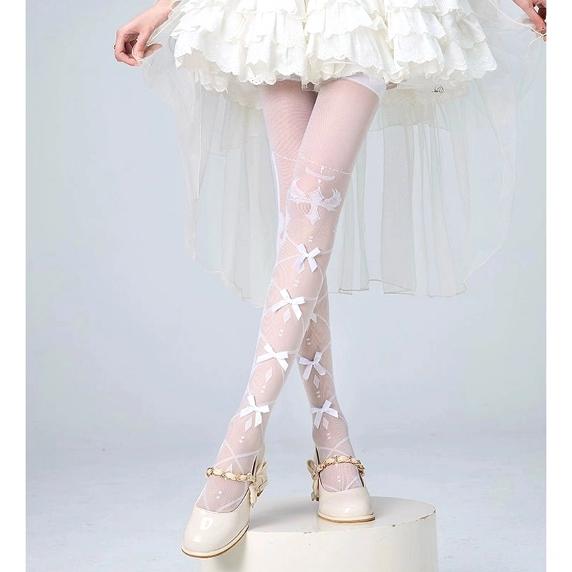 White with bow Jirai Kei over-the-knee velvet socks featuring exquisite bow details and intricate lace patterns, styled on model in white ruffled dress with beige Mary Janes, front view showcasing sophisticated design elements