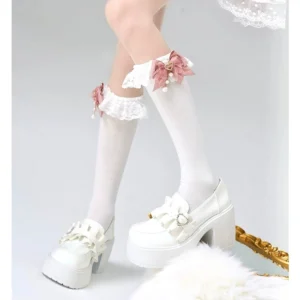 White mid-calf lace bow socks with pink bow and tiny flower decorations paired with white platform loafers, front view of lower legs