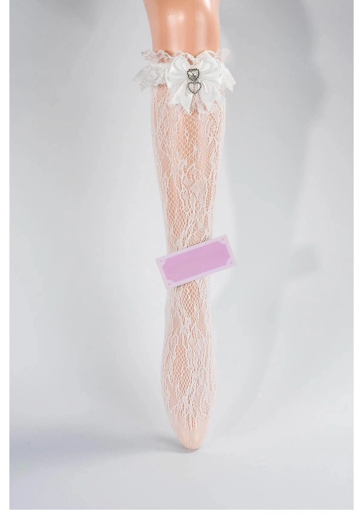 White lace mid-calf Jirai Kei socks with ruffled cuff, white bow and heart rhinestone embellishment, front full view on mannequin leg