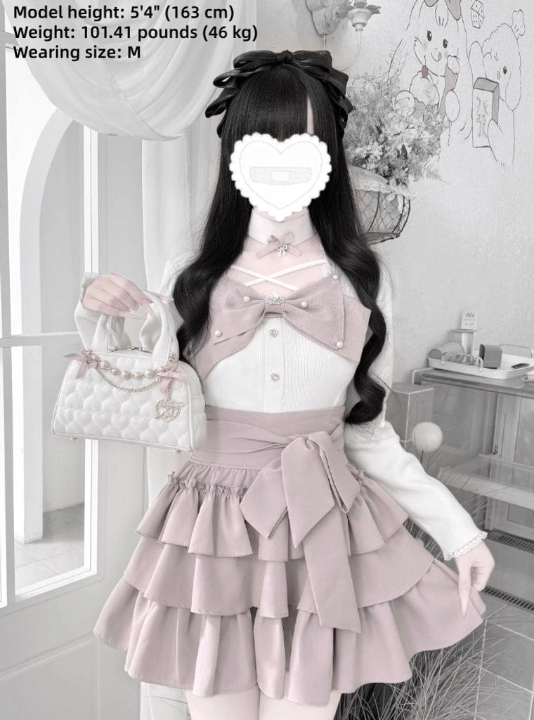 White and pink Jirai Kei coordinate on model wearing long-sleeve top with tiered ruffle skirt heart face mask and handbag three-quarter view