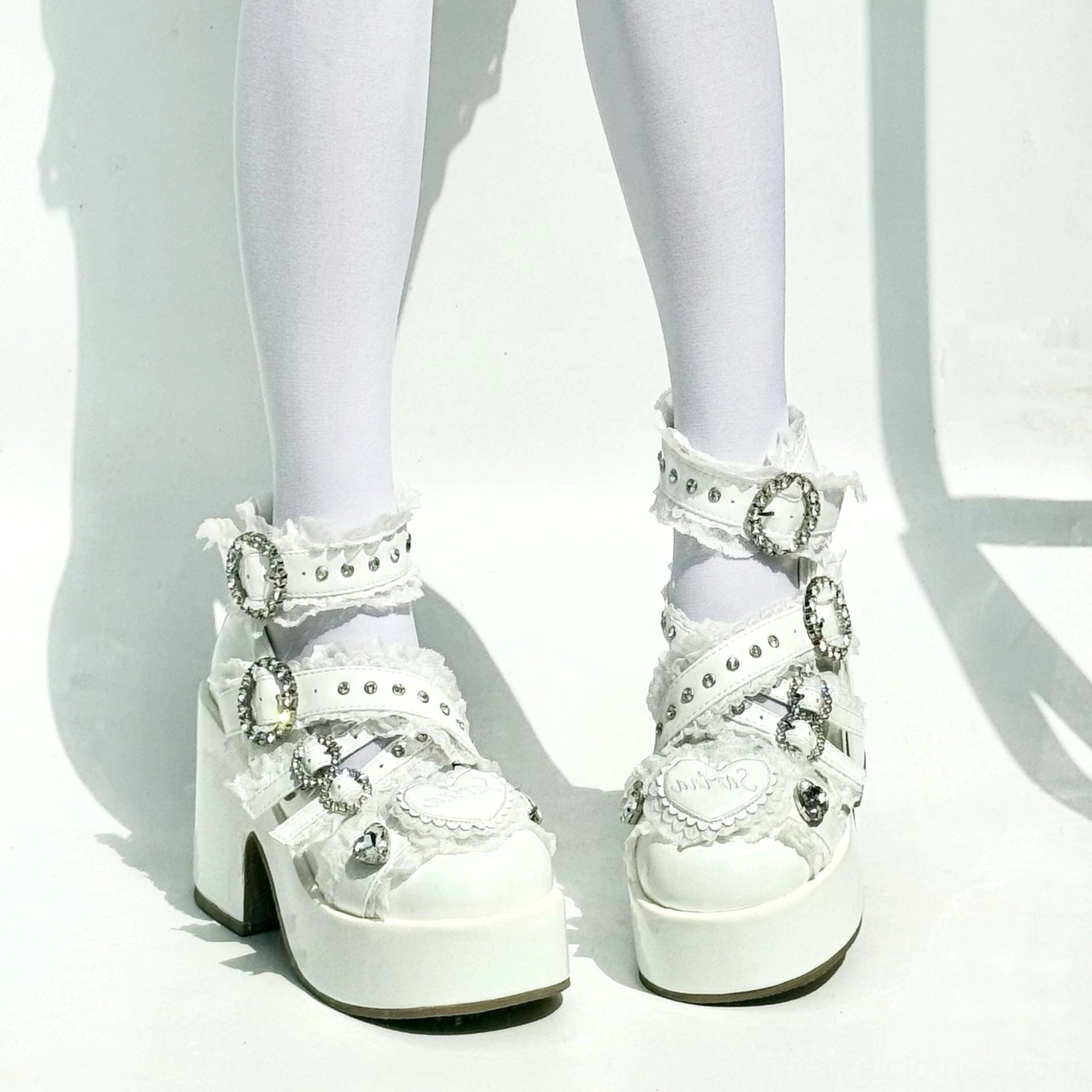 Pure white Jirai Kei platform high heels with crystal buckled straps heart toe decor on model legs