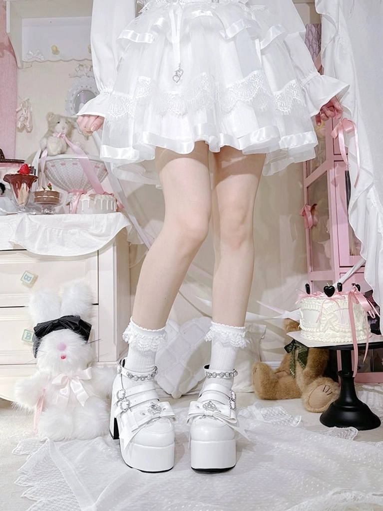White patent leather Jirai Kei platform chunky heel shoes with rhinestone double buckle straps, styled with ruffled white lace mini skirt
