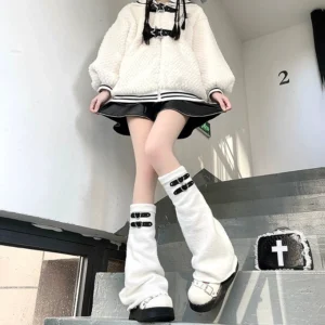White knitted leg warmers featuring black dual leather buckles worn with fuzzy varsity jacket and mini skirt, front view Jirai Kei styling