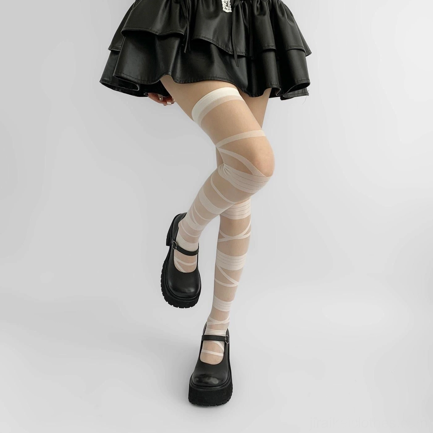 Y2K Jirai Kei white strappy thigh-high sheer socks with crisscross bandage design worn with black ruffled mini skirt and platform Mary Jane shoes side view